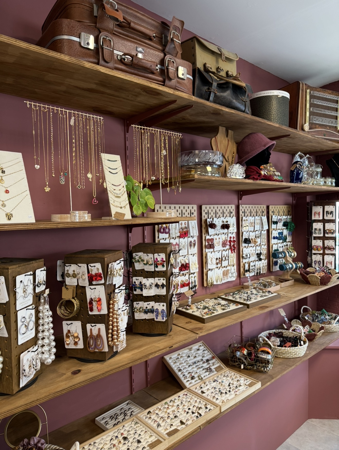 Wand met vintage sieraden: gouden kettingen, oorbellen, ringen en armbanden op houten schappen